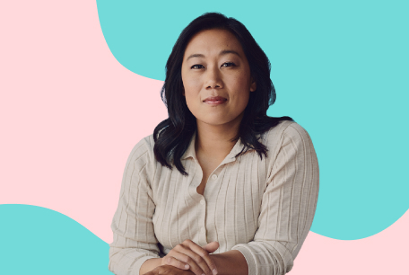 Priscilla Chan, co-CEO of the Chan Zuckerberg Initiative, looking at the camera with her arms folded and in front of a pink and blue illustrated background.
