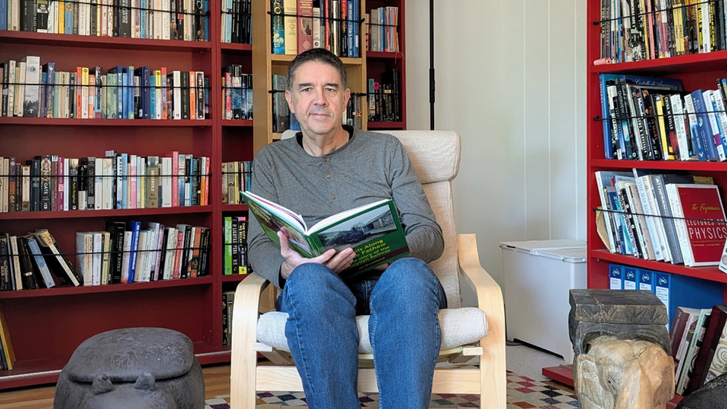 A man sits in a chair with a book open